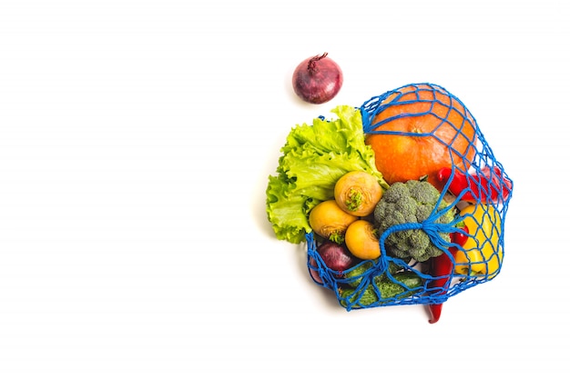 Bolsa textil de malla llena de verduras mixtas. Concepto de comida sana y cero residuos. Aislado en blanco