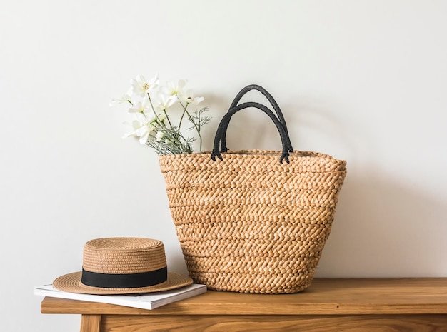 Una bolsa de verano de paja de mimbre, un sombrero y una revista en un banco de madera Temporada de verano