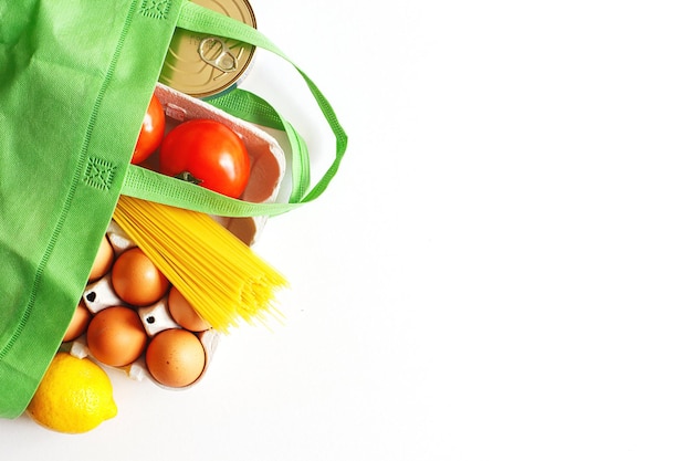 Bolsa verde llena de alimentos saludables sobre un fondo blanco Vista superior huevos vegetales de frutas