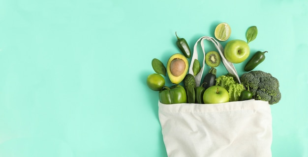 Bolsa con verduras y frutas sobre fondo de menta