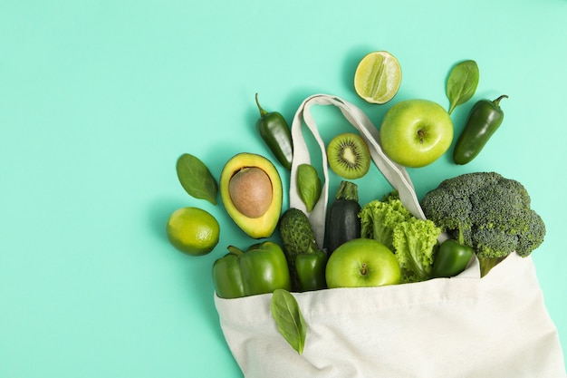 Bolsa con verduras y frutas sobre fondo de menta