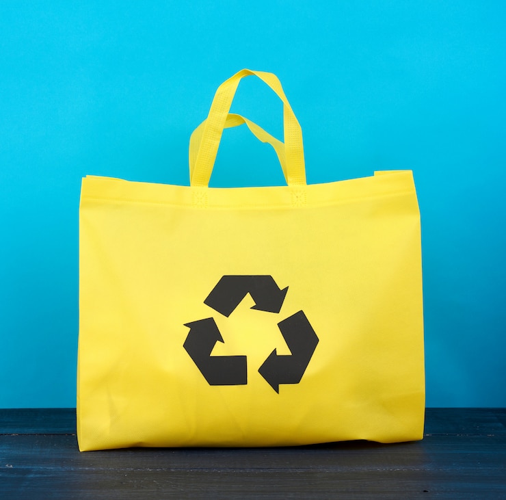 Foto bolsa de viscosa amarilla reutilizable completa sobre fondo de madera azul