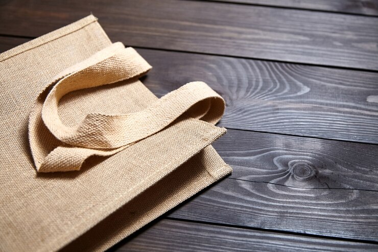 Bolsa de yute comercial reutilizable sobre mesa de madera marrón