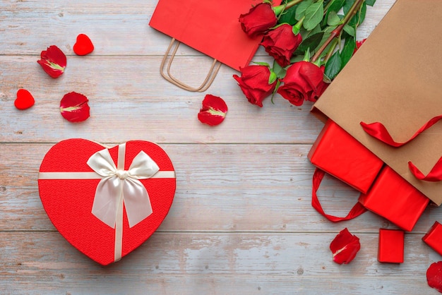 Bolsas de artesanía de compras rojas con regalos de los amantes caja de embalaje en forma de corazón rosas y pétalos