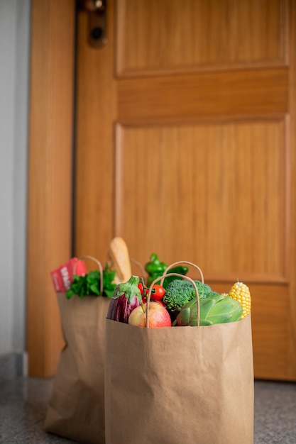 Foto las bolsas de compra de alimentos se colocan en la puerta de la casa o apartamento. entrega de verduras y frutas durante cuarentena y autoaislamiento.