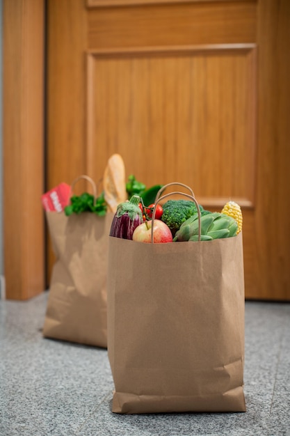 Foto las bolsas de compras de alimentos están en la puerta de la casa o apartamento la entrega de verduras y frutas durante la cuarentena y el autoaislamiento