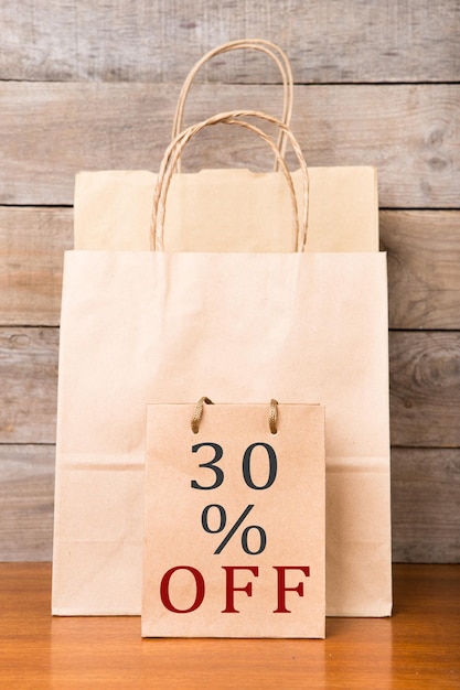 Bolsas de compras con inscripción 30 OFF sobre fondo de madera