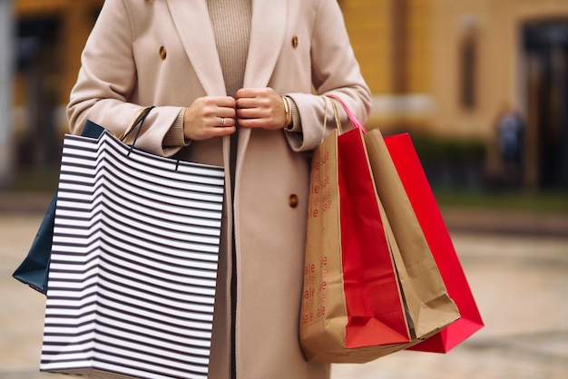 Bolsas de compras en las manos Mano de mujer joven con bolsas multicolores con compras