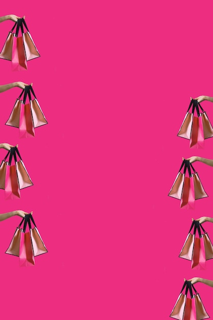 Bolsas de compras en manos de mujeres sobre fondo rosa