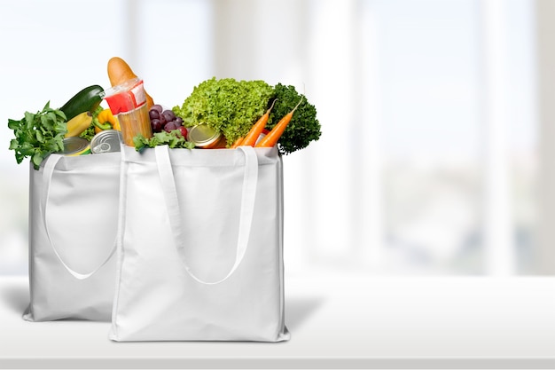 Foto bolsas con pan y variedad de verduras sobre fondo brillante