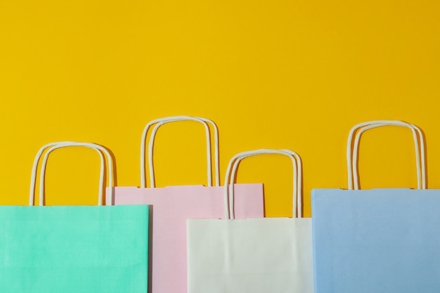 Bolsas de papel de colores en blanco sobre fondo amarillo