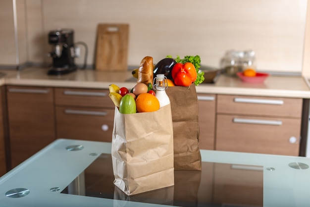 Bolsas de papel llenas con alimentos en la mesa.