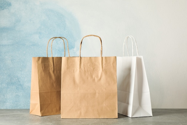 Bolsas de papel en mesa gris contra azul