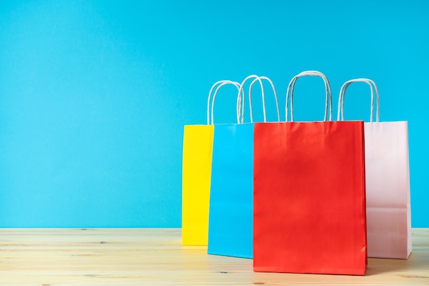 Bolsas de papel multicolor para buenas compras en la mesa y fondo de color con metanfetamina para el texto.