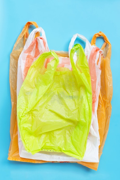 Bolsas de plástico de colores sobre fondo azul. Concepto de contaminación ambiental