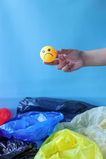 Bolsas de plástico desechables de colores con emoticono triste. El concepto de residuos, reciclaje y medio ambiente.