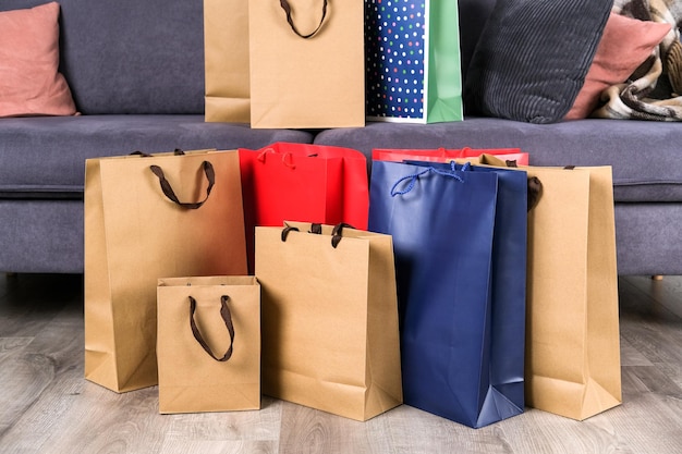 Bolsas de regalo y muchas bolsas de papel después de comprar en casa en la sala de estar junto al sofá