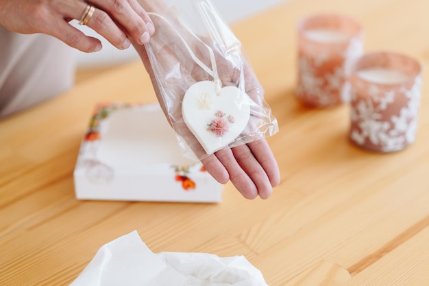 Bolsita florentina blanca en forma de corazón con flores Flores secas en manos de mujeres