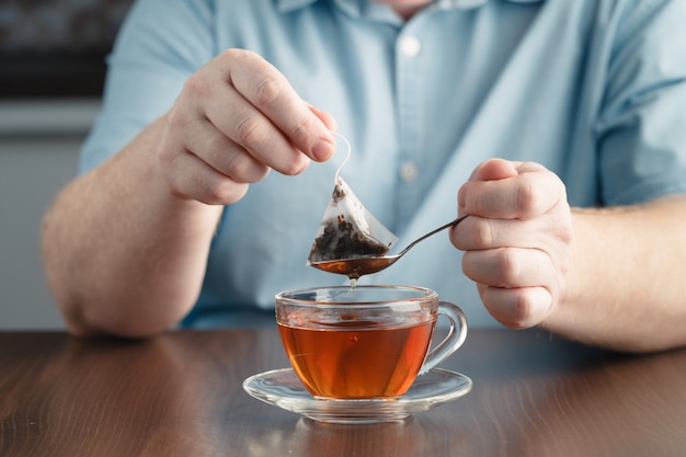 Bolsita de té en la taza con agua caliente