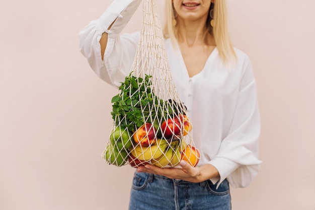 Bolso de compras de cadena con frutas en manos de una mujer joven. Bolsa ecológica reutilizable para ir de compras.