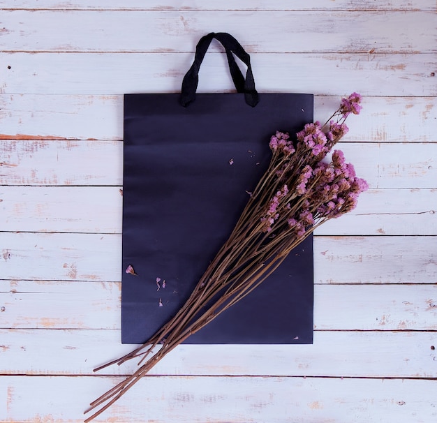 Bolso de compras y flores secas en el fondo de madera