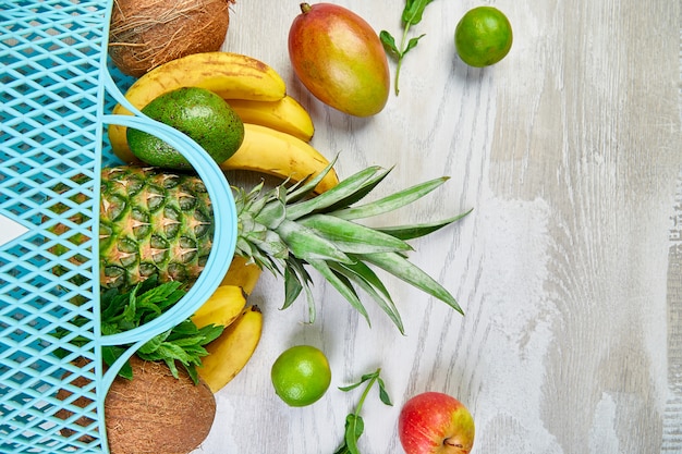 Bolso de compras con frutas exóticas orgánicas sobre fondo blanco.