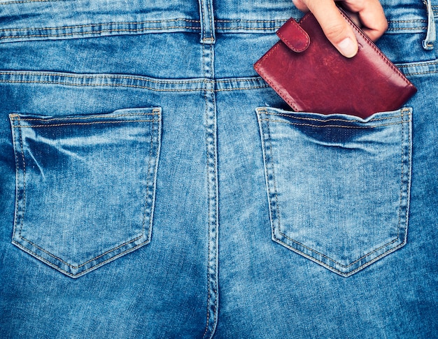 El bolso de cuero marrón se encuentra en el bolsillo trasero de los tejanos.