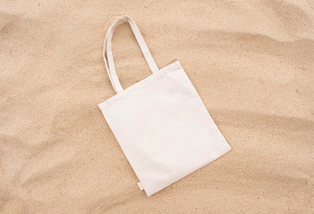 Bolso de lona na praia de areia mock up design