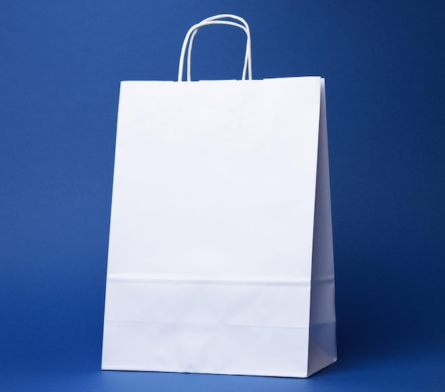 Bolso de papel branco descartável com alças em fundo azul de perto