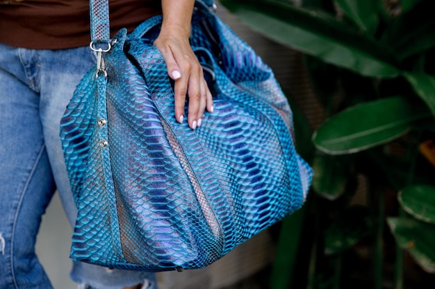 Bolso grande de cuero azul clásico de pitón de moda en manos de mujer