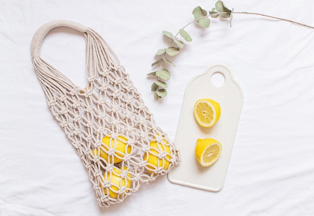 Bolso de macramé para compras hecho a mano con limón sobre fondo blanco de algodón