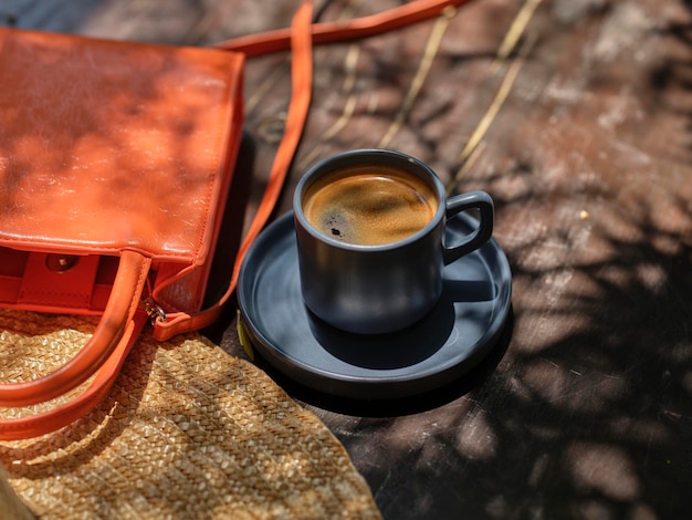 Bolso naranja de sombrero de paja y delicioso café en la mesa de madera