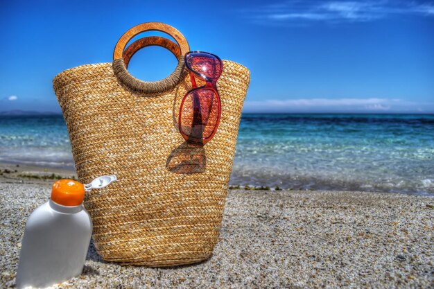 Bolso de paja y loción bronceadora junto al mar Procesado para efecto de mapeo de tonos hdr