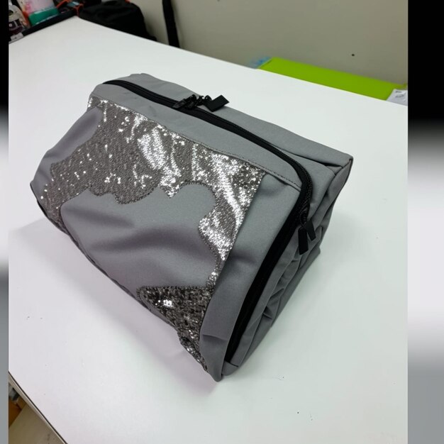 Foto un bolso plateado con una correa negra que dice 'lentejuelas'