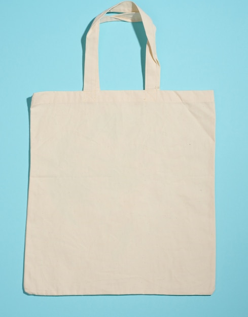 Foto bolso tote de lona beige ecológico de lino vacío para la marca sobre fondo azul. bolsa transparente reutilizable para comestibles, maqueta. endecha plana