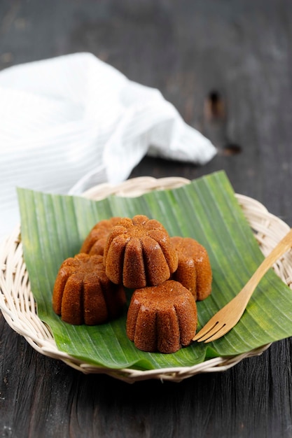 Bolu Sakura Gedämpfter Karamellkuchen aus Karamell mit Kuchenteig aus Eierzuckermehl und Butter, serviert auf Holzplatte mit Bananenblatt-Kopierfläche für Text