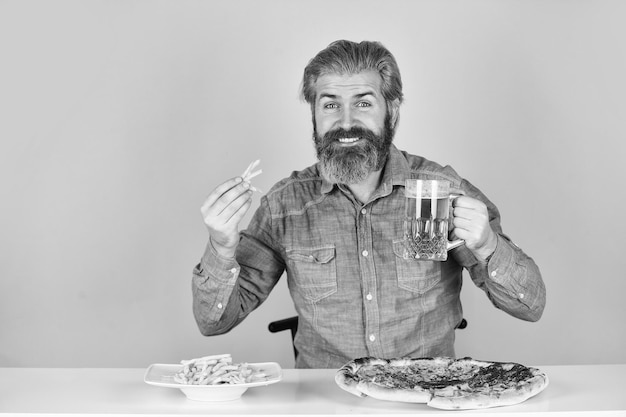 Bom apetite Ainda com fome Cerveja e comida Jantar no pub Homem com fome vai comer pizza batatas fritas e beber cerveja Restaurante de pizzaria Homem alegre hipster barbudo come pizza Conceito de festa de pizza