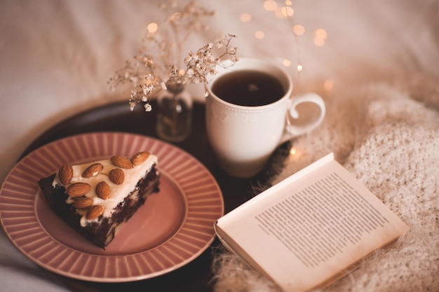 Bom dia com uma xícara de café fresco e closeup de bolo de chocolate. Lendo na cama. Inverno.