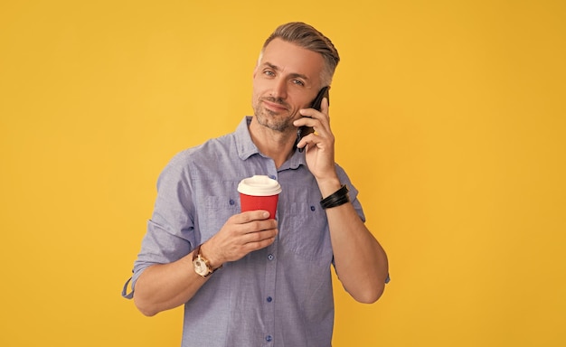 Bom dia comunicação homem bonito usa smartphone com xícara de café