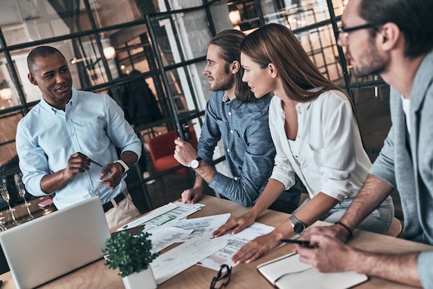 Bom dia de trabalho. Vista superior de jovens empresários discutindo algo enquanto estão sentados no escritório