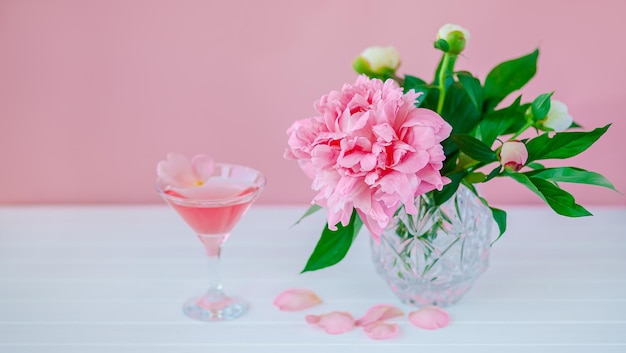 Bom Dia. Peônias rosa em um vaso de cristal em um fundo rosa de madeira, copie o espaço, close-up.