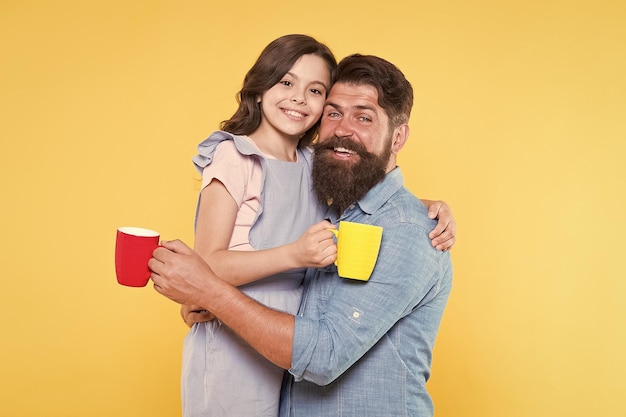 Bom dia Tomando café juntos Adorável tradição familiar Beber chá Homem barbudo e garota feliz segurando canecas Pai e filha bebida quente Beber água Beber suco fresco Conceito de café da manhã