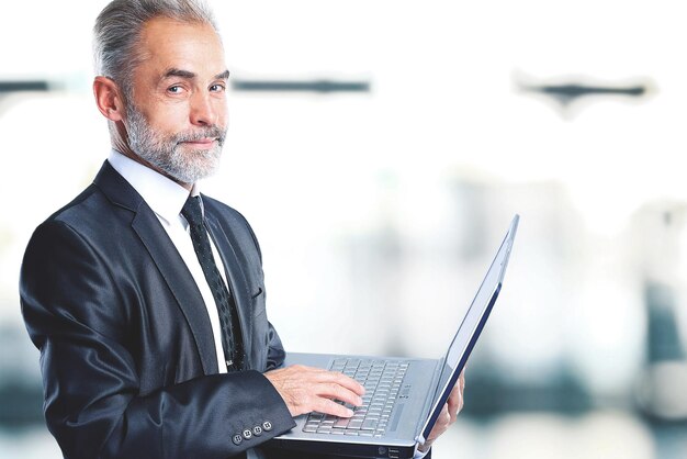 Bom empresário na idade mantém o laptop isolado em um fundo branco