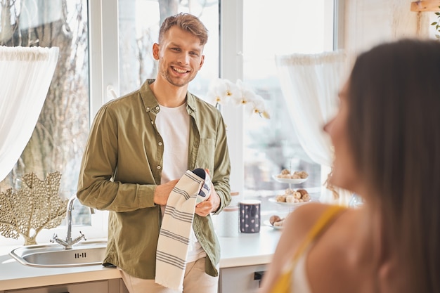 Bom fim de semana. Homem moreno encantado e positivo com um sorriso no rosto enquanto olha para a namorada