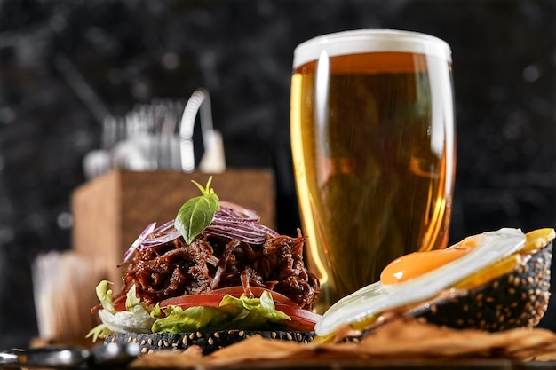 Foto bom hambúrguer com carne cebola cebola doce queijo alface tomate em papel de artesanato com um copo de cerveja