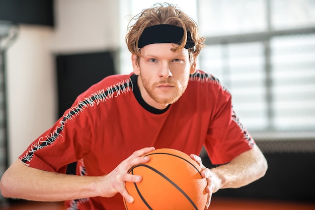 Bom jogador. ginger man em um sportswear vermelho jogando basquete