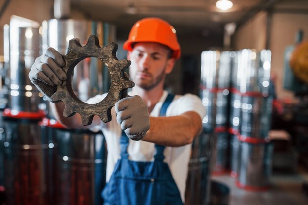 Bom material. Homem de uniforme trabalha na produção. Tecnologia industrial moderna.