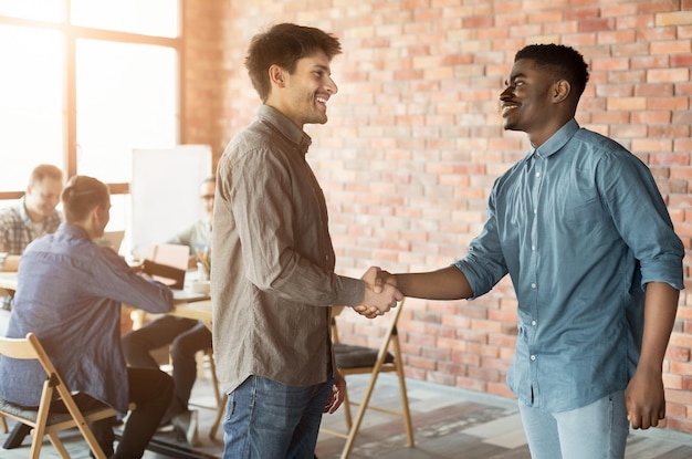 Foto bom trabalho. aperto de mão de dois homens para fechar negócio, parceiros alegres se cumprimentando no escritório, cópia espaço