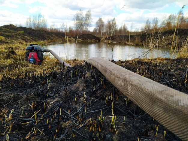 Foto bomba de água elétrica colocada na costa da lagoa bomba de água portátil na costa da lagoa do país, extinguindo um incêndio natural queimando solo e vegetação de turfa