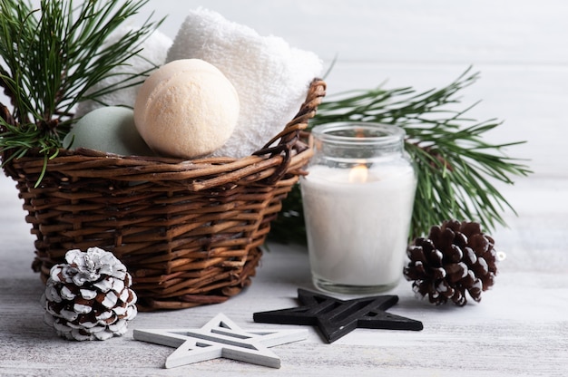 Bombas de baño en canasta en composición de SPA de Navidad con vela encendida